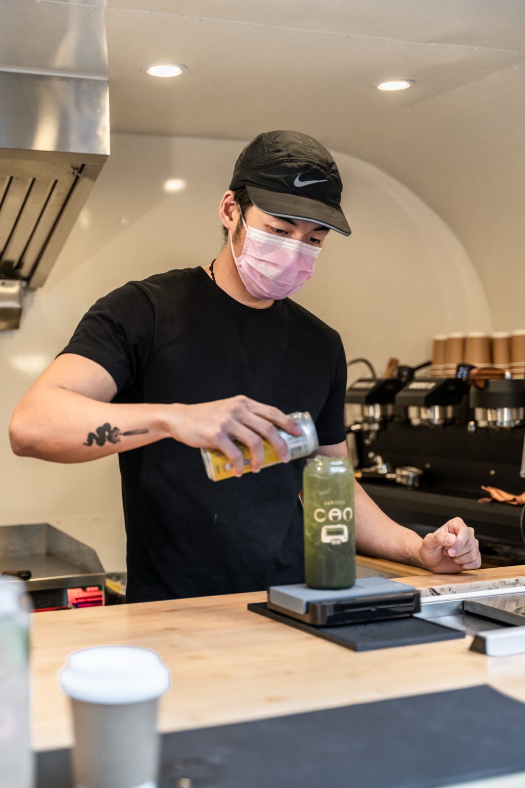 A Project CAN barista pouring an iced drink at the caravan bar.