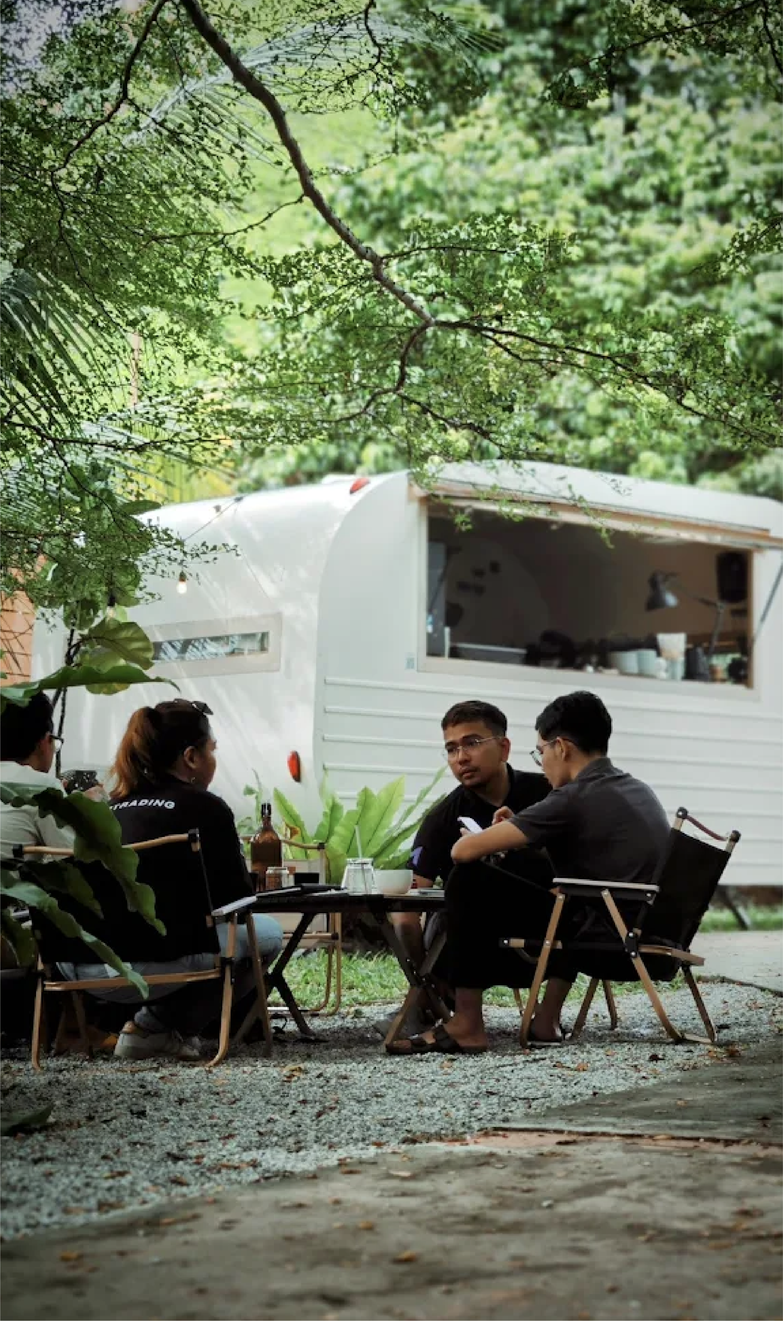 Friends gathered around camping chairs outside the Project CAN caravan.